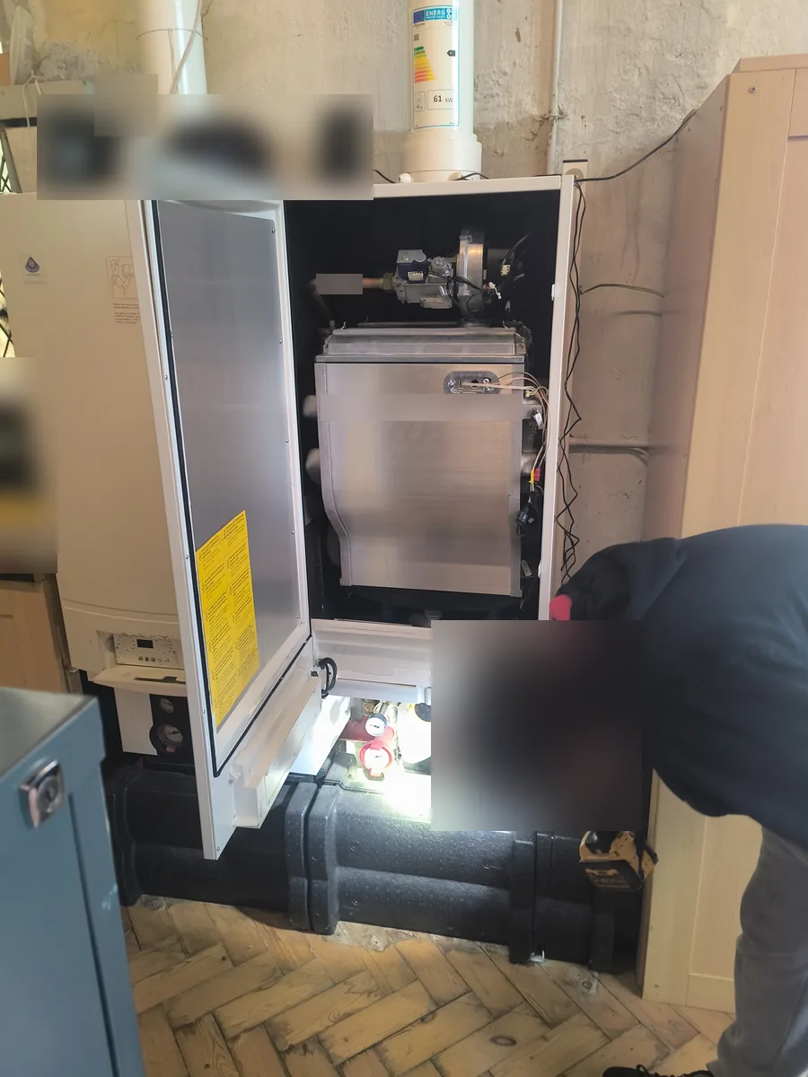 Engineer checking the base of a commercial boiler with a torch during a service in Haverhill