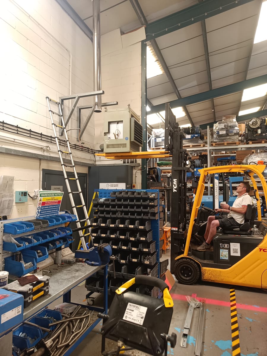Forklift lifting an industrial heater for wall mounting