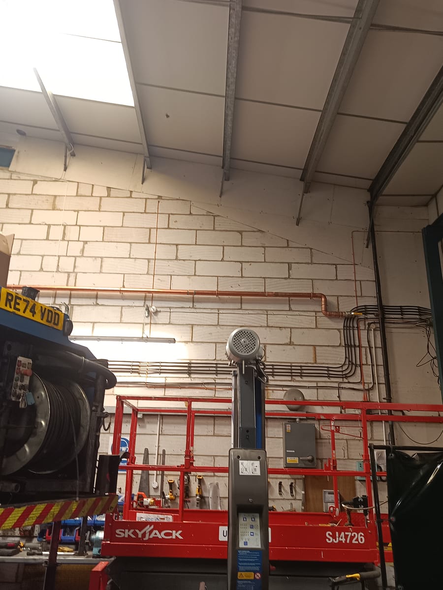 Skyjack lift beside high-level copper wall pipework
